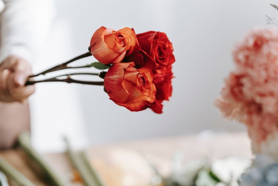 A florist holding fresh orange and red roses