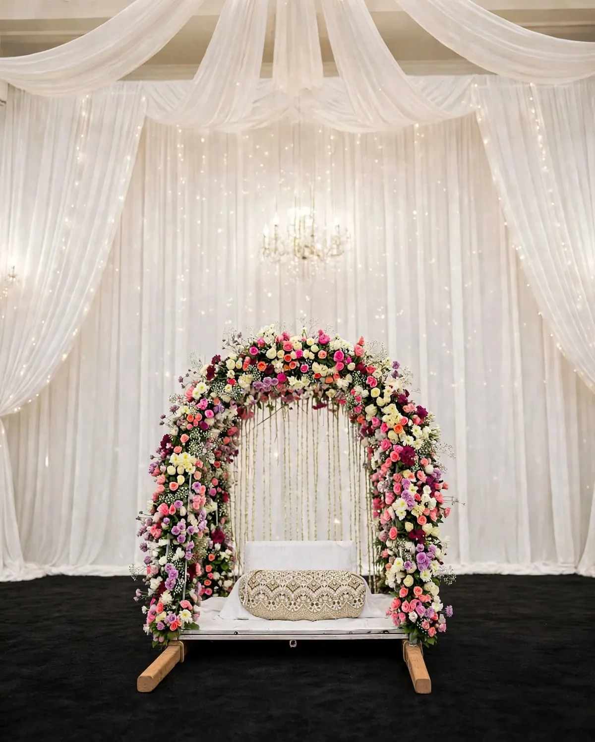 Pastel Flower Arch Jhoola: Swing seat under an arch of pink, white and purple flowers with white drapes and fairy lights, GuleGul Flowers Lahore