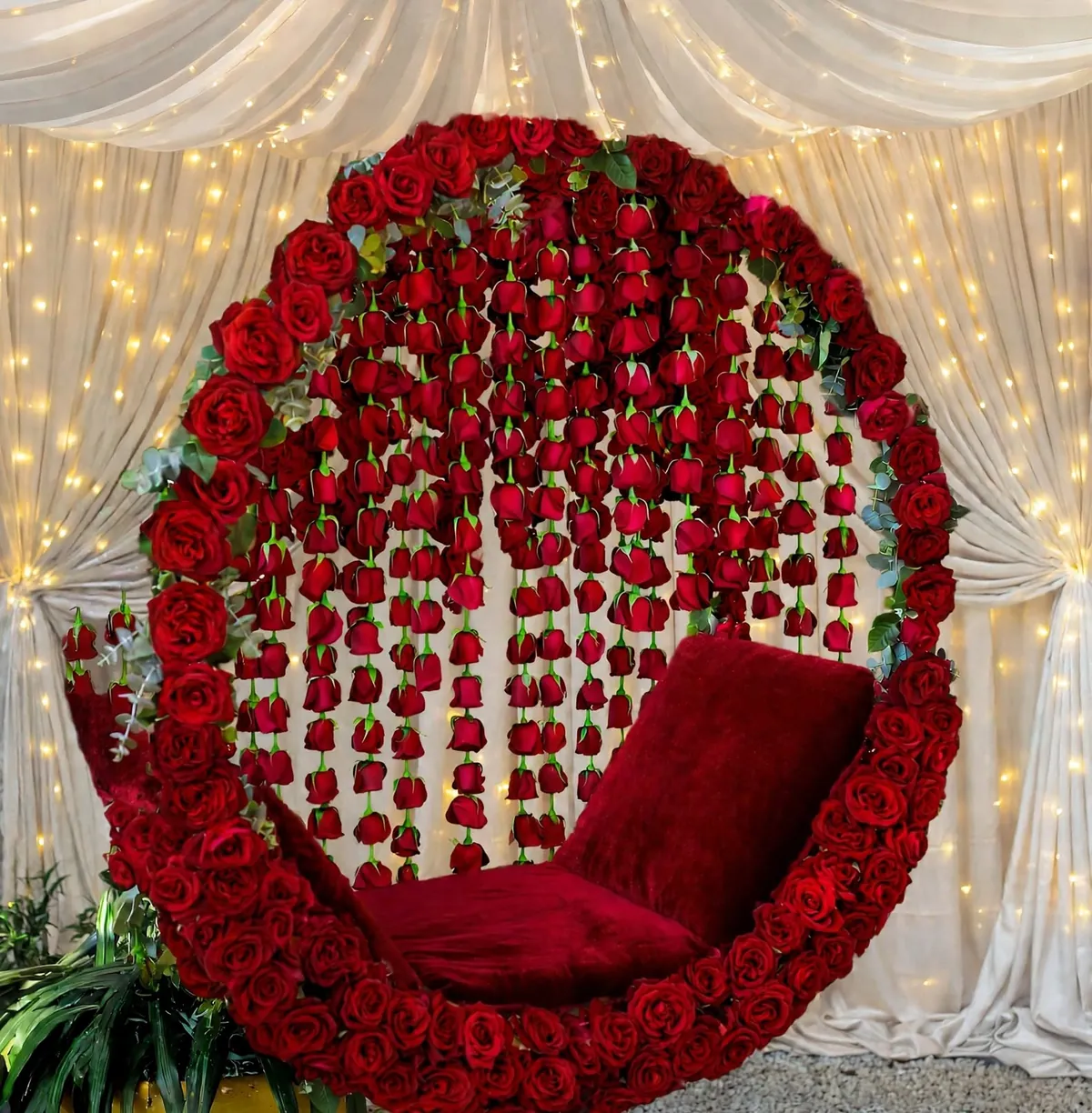 Red Rose Round Jhoola: Round seat framed in red roses with red rose strings hanging inside, in front of white drapes and fairy lights, GuleGul Flowers Lahore