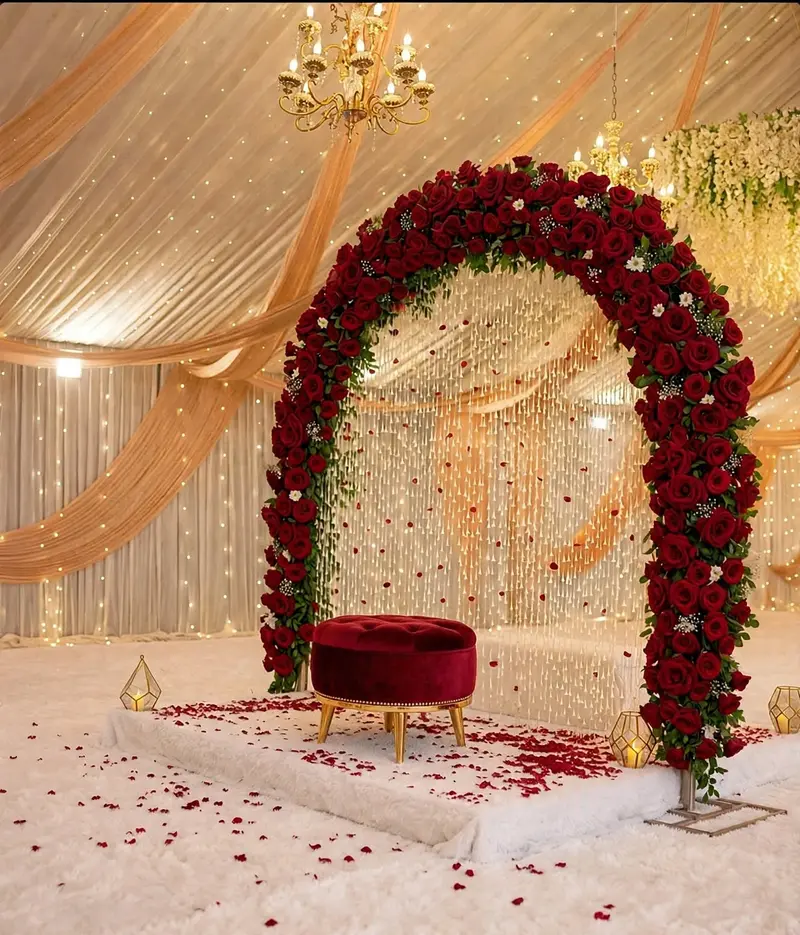 Red Rose Nikkah Arch for Outdoor Tent: Round red rose arch with a velvet stool and rose petals under a decorated tent, GuleGul Flowers Lahore