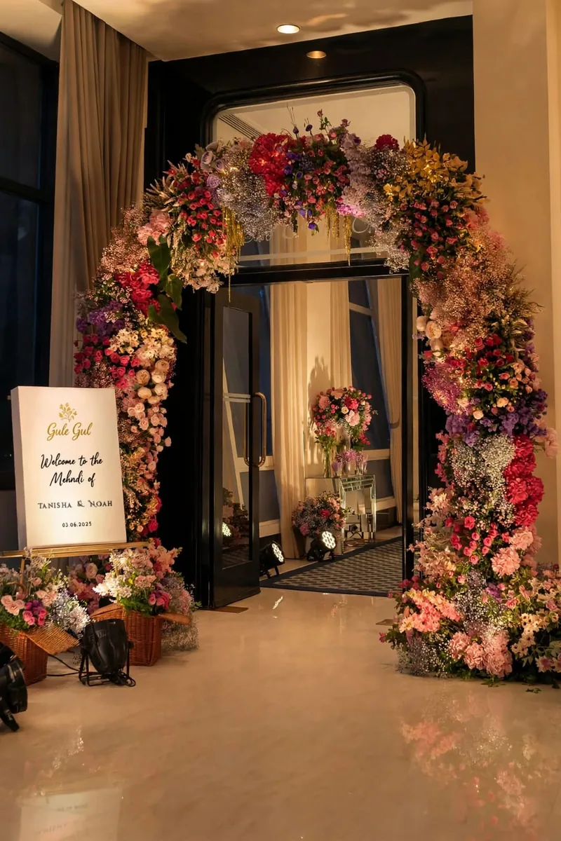 Mixed Flower Door Arch: Arch of pink, red, purple and white flowers around a glass door with a welcome sign and flower baskets, GuleGul Flowers Lahore
