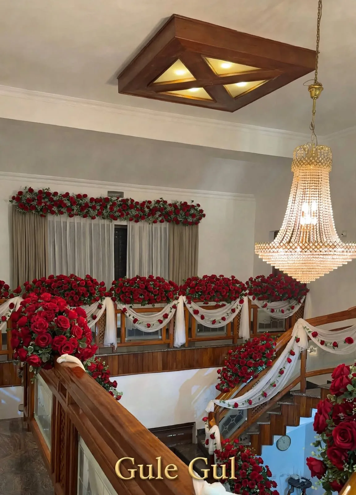 Red Rose Balcony and Stair Decor: Red roses along a balcony and stair railing with white drapes and a rose garland over the window, GuleGul Flowers Lahore